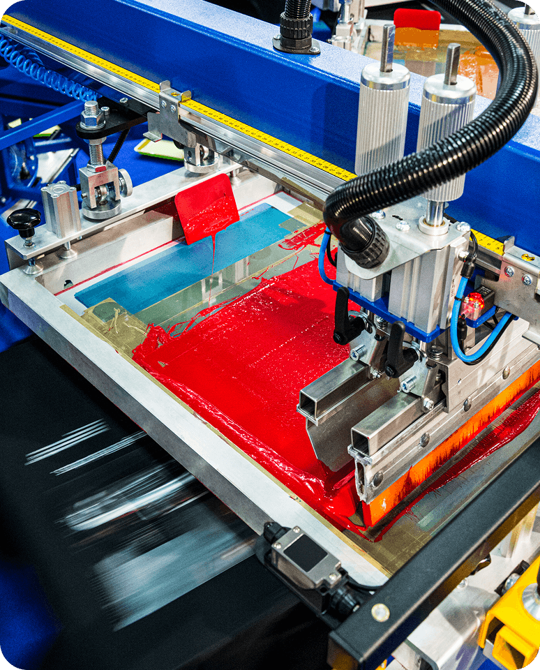 Screen printing machine applying red ink.