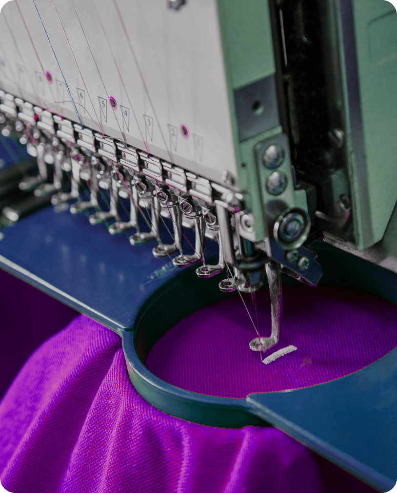 Embroidery machine stitching on purple fabric.