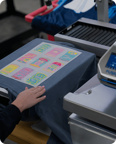 Person using a heat press machine to print colorful designs on fabric.